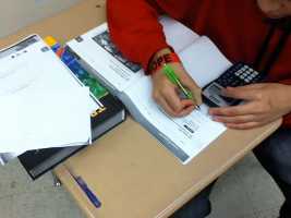 student with calculator writing in workbook